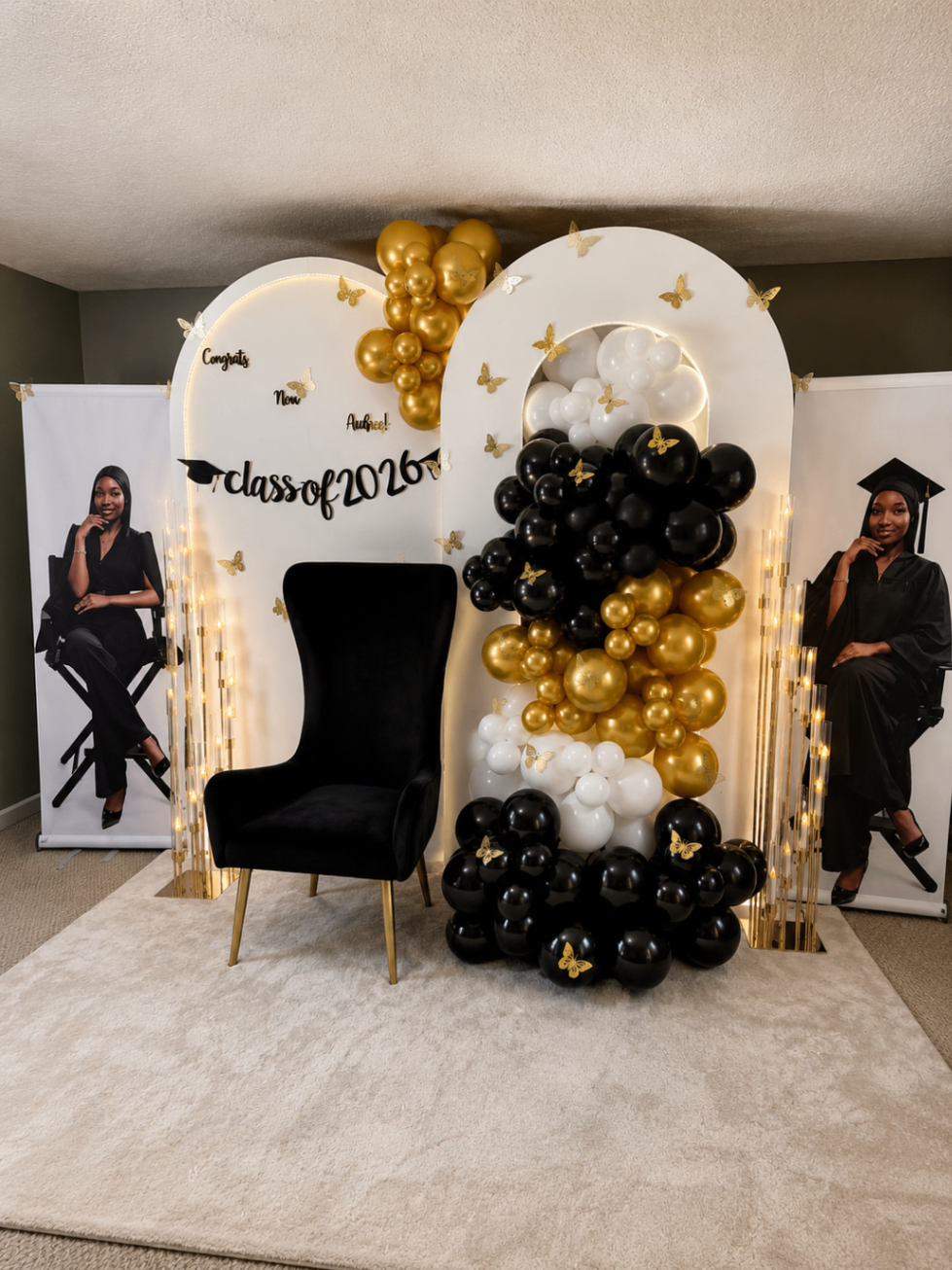 Graduation chair setup with black, white, and gold balloons styled on a soft ivory rug.