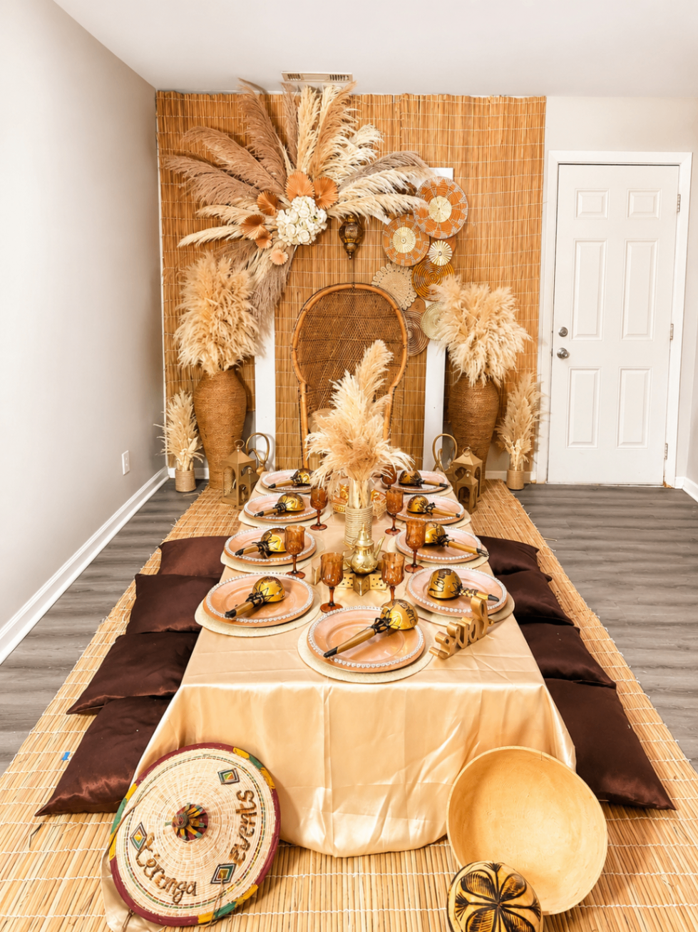 Gold-toned ceremony table with layered décor, woven textures, and floor seating.