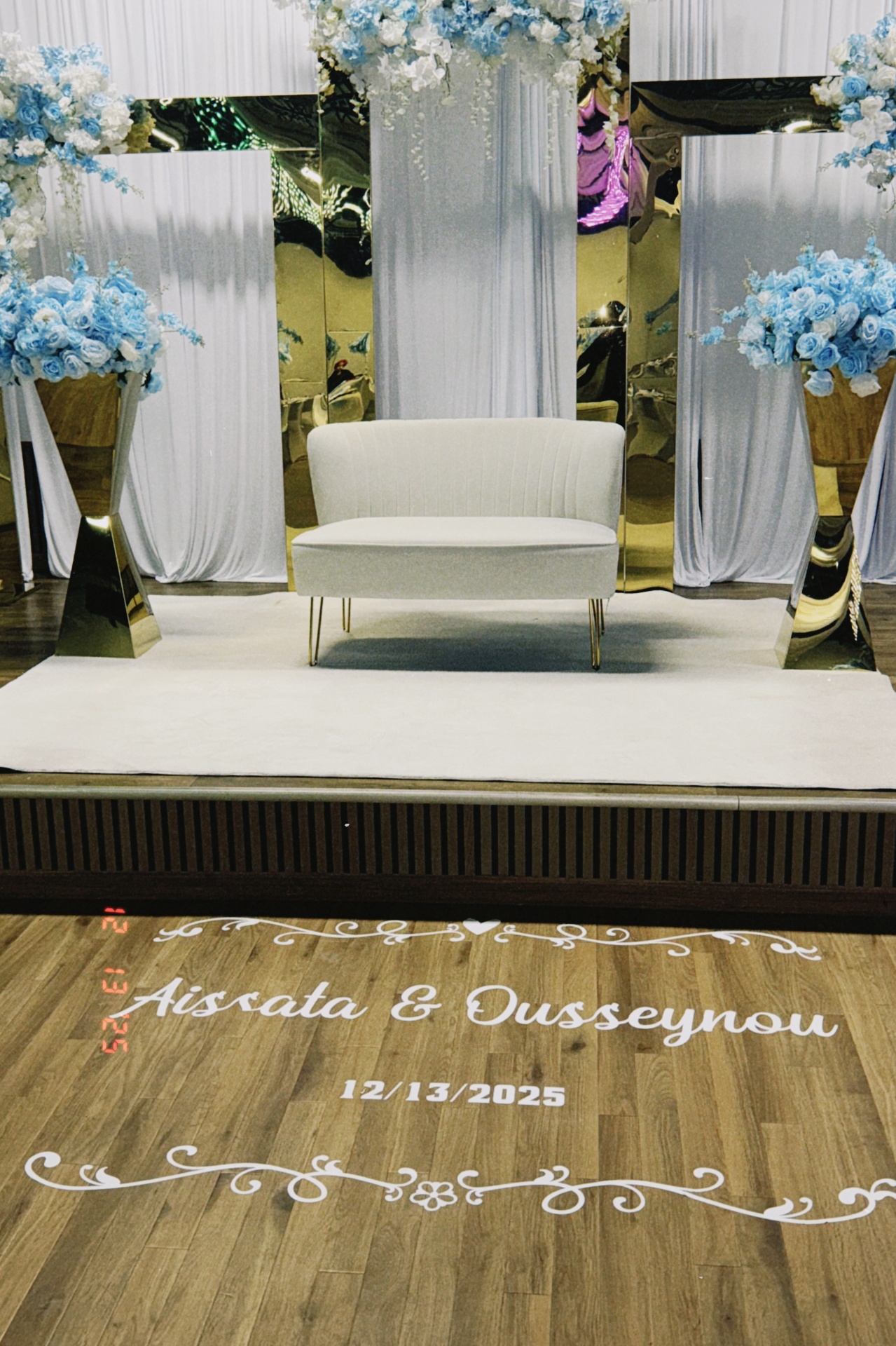 Wedding sweetheart stage with mirrored panels, blue and ivory florals, and personalized dance floor decal.