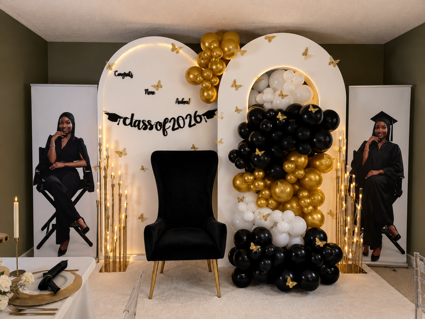 Black, white, and gold graduation setup with illuminated arches and statement balloons.