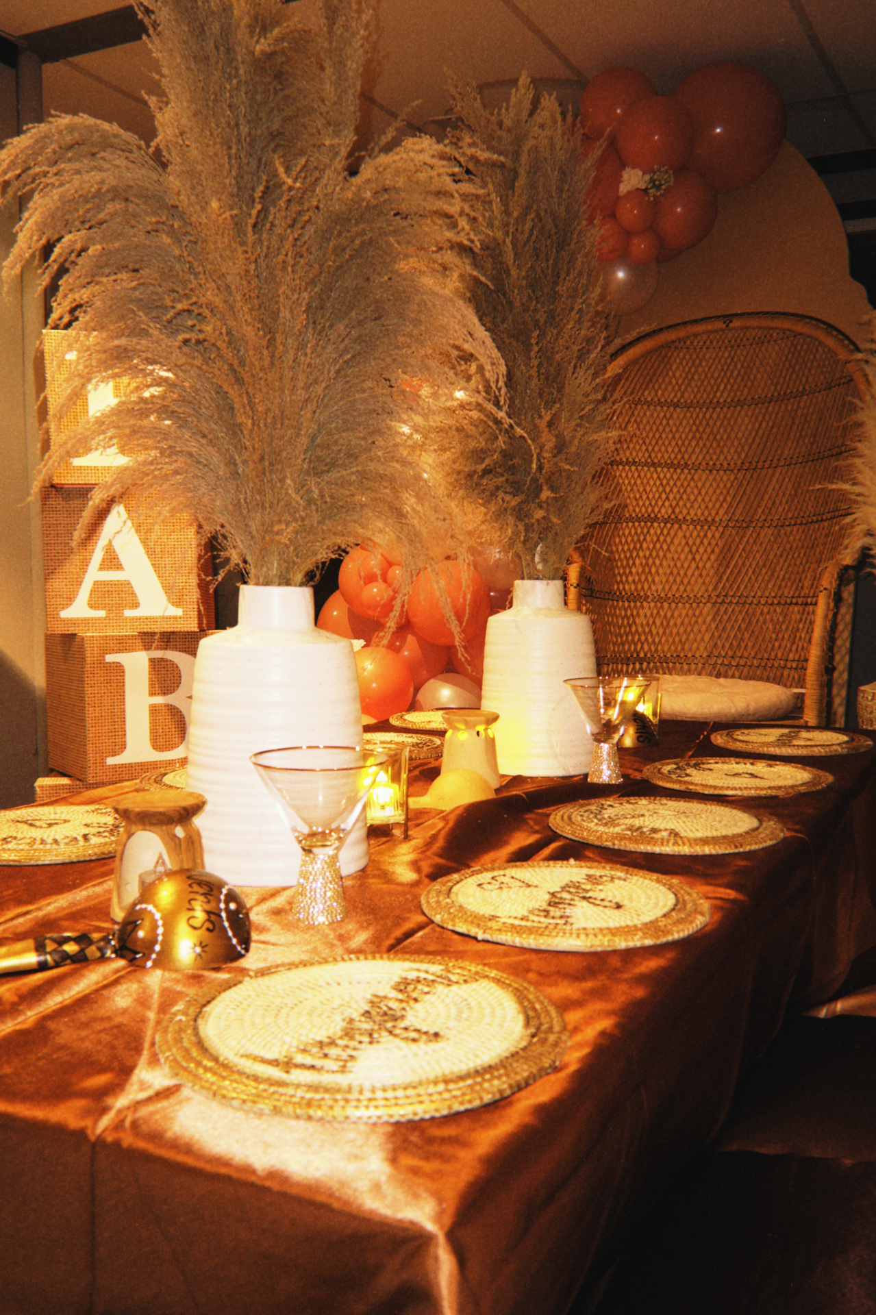 Rouye Time banquet table with bronze satin linens, woven chargers, pampas, and candlelight.