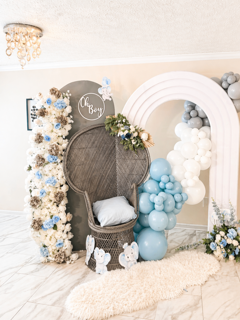 Close view of Oh Boy setup with wicker chair, balloon styling, and floral wall.