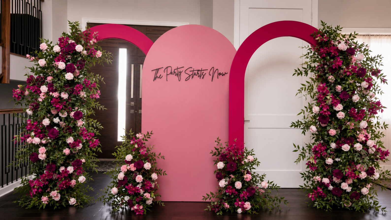 Pink floral event backdrop with arched panels and layered arrangements.