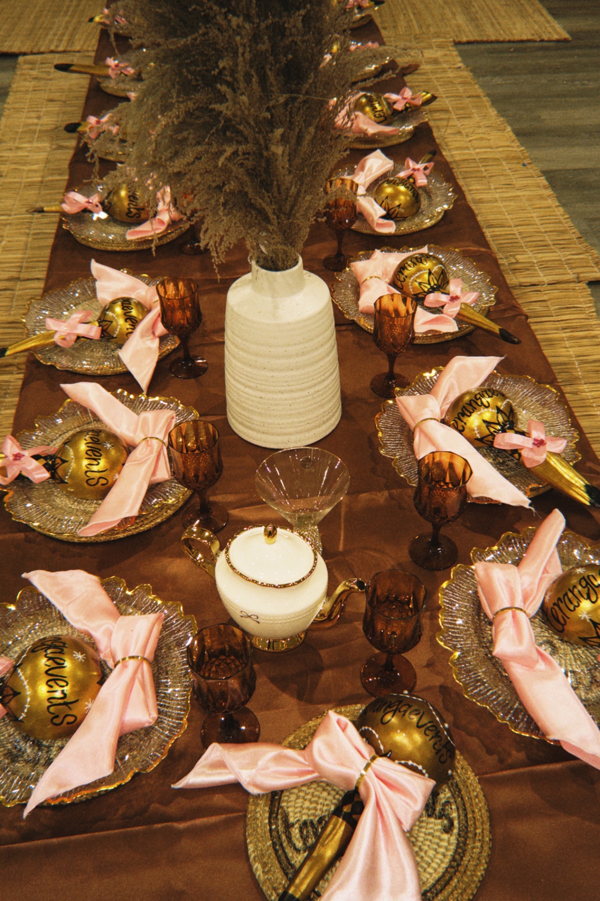 Close Henne Time tablescape detail with bronze satin linens, blush napkins, amber stemware, and gold ceremonial accents.